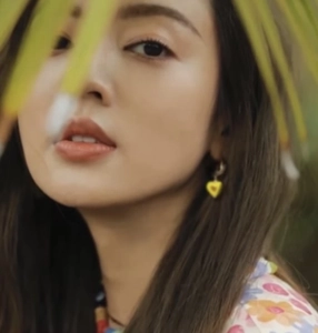 Close-up of heart-shaped yellow Murano glass earrings worn by a model in nature
