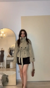 Detail of khaki short trench coat featuring waist tie belt and double-breasted buttons