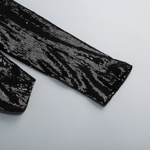 Détail de sequins argentés haute densité formant un motif zébré sur une manche noire