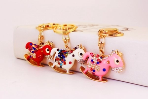 Close-up of diamond-studded rocking horse keychains in red, white and pink colors
