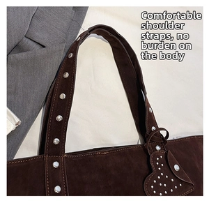 Detail of studded brown suede tote shoulder strap with silver heart-shaped charm