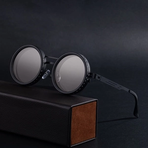 Detailed side view of vintage steampunk round sunglasses on a textured case