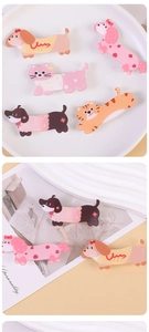 Flat lay of colorful acrylic cartoon dog and cat pins on a minimalist cream background