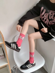 Detail of pink crew socks with white YEAH letter pattern paired with black sneakers