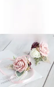 Detail of pink and burgundy silk rose wrist corsage with gold leaves and satin ribbon