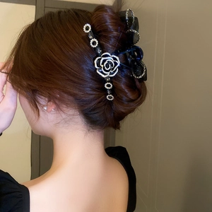 Pince à cheveux noire élégante avec camélia en strass et nœud en tulle sur modèle