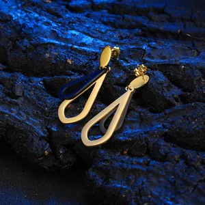 Macro detail of geometric hollow teardrop earrings with gold finish and dark contrast coating