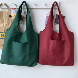 Minimalist canvas tote bags in dark green and deep red hanging on a white wall hook