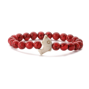 Detailed shot of red marbled beads and white dolphin charm on an elastic bracelet