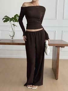 Detail view of deep brown two-piece set featuring pleated texture and wide-leg trousers