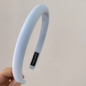 Detailed view of light blue padded headband featuring a hand made woven textile label