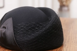 Detail of wool felt beret featuring delicate black mesh veil and satin bow decoration
