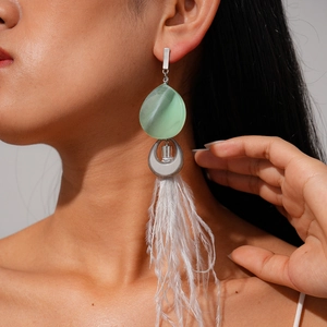 Detail of bohemian long feather earrings with light green resin teardrop on model
