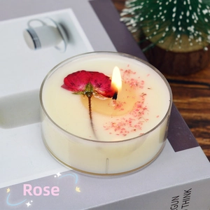Close-up of a burning handmade rose scented candle with dried petals in a clear glass jar