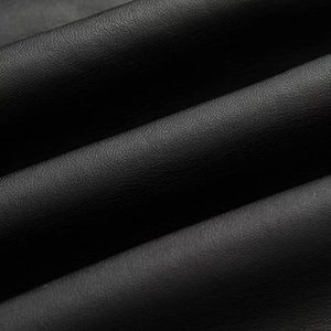 Close-up of premium black faux leather texture and detailed grain on a short trench coat