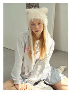 Furry white cat ear hat with earflaps worn with a casual hoodie and blue pleated skirt