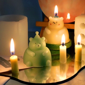 Creative 3D teddy bear scented candles in cream and green on a reflective surface