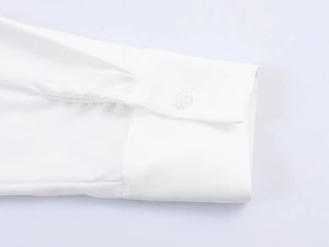 Detail shot of a white shirt cuff featuring a neat button closure and fine stitching