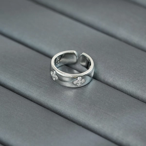 Macro shot of silver wide band ring with clover flower pattern and zircon inlay
