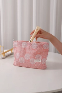 Pink linen makeup bag with white flower embroidery and zipper shown in hand use