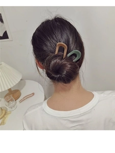 Detail view of khaki and green U-shaped hair pins securing a bun on model hair