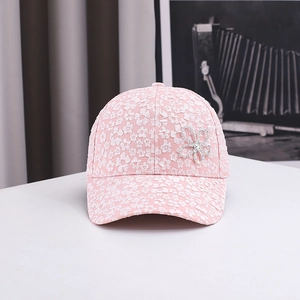 Detail of pink baseball cap featuring floral lace embroidery and rhinestone accents