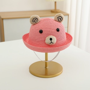 Détail d'un chapeau de paille rose pour enfants avec oreilles d'ours et cordon