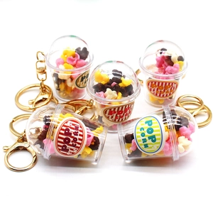Detailed close-up of five mini popcorn bucket keychains with colorful faux kernels