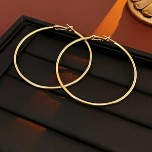 Detailed view of glossy golden round hoop earrings placed in a premium black jewelry box