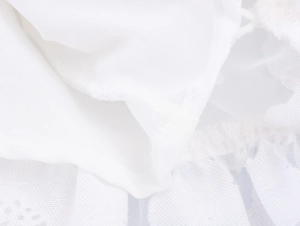Detailed macro view of white floral lace patchwork and pleated fabric on dress hem