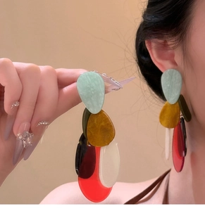 Detail view of multi-color bohemian acrylic resin drop earrings on a model with artistic design