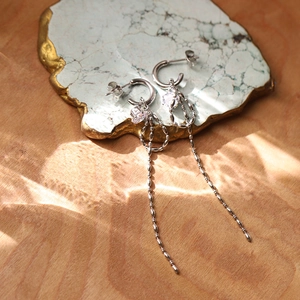 Silver bow earrings with heart cubic zirconia and long chain tassels on a marble tray