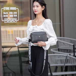 Close-up of black V-quilted camera bag with patterned wide strap and small round coin purse