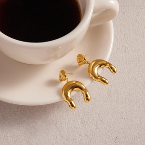Vue détaillée des boucles d'oreilles dorées en forme de U sur une tasse à café