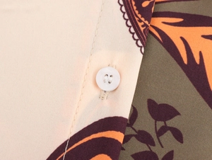Detailed close-up of white buttons and botanical print fabric with neat stitching
