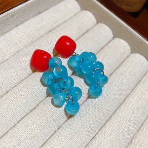 Detail of square resin earrings with blue grape tassel on cream velvet jewelry tray