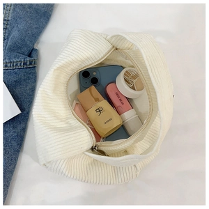Top view of open white corduroy handbag showing interior storage for cosmetics