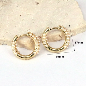Detailed view of gold pearl hoop earrings with dimensions 17mm by 19mm on stone