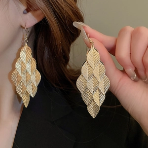 Golden multi-layer metal leaf fringe drop earrings shown on model for elegant style