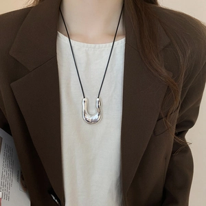 Detailed view of a silver lava U-shaped pendant on a minimalist black cord necklace