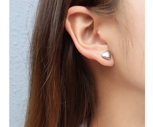 Close-up of heart-shaped silver earrings worn to show fashion style and metallic finish