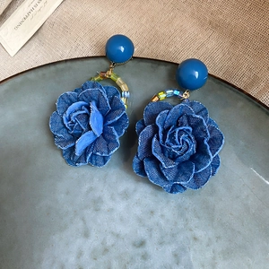 Détail de boucles d'oreilles rose en jean avec perles bleues sur un plateau décoratif
