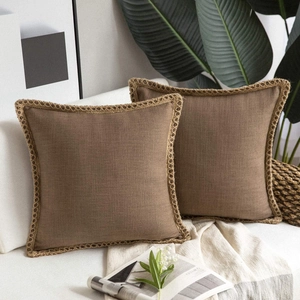 Close-up of brown linen pillow cover with woven rope trim on a white sofa with a throw