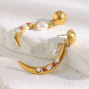 Macro shot of 18K gold horn earrings with pearls and pink crystals on stone base