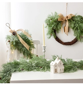 Detail of green Christmas wreath and garland with burlap bows and small pinecones