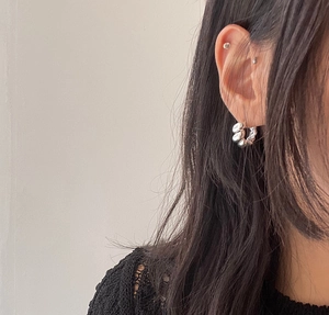 Close-up of model wearing twisted sterling silver hoop earrings with a minimalist rope design