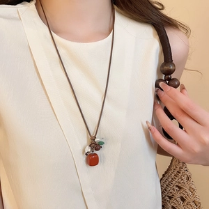 Ethnic style necklace detail featuring red stone and silver beads on a dark wax cord