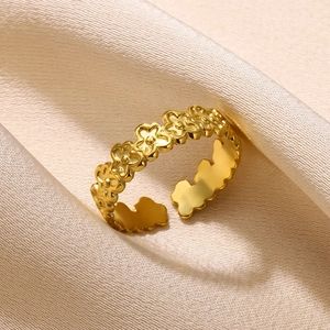 Detail of gold floral pattern stainless steel open ring on soft silk background