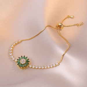 Elegante bracciale a girasole dorato con zirconi verdi su sfondo di seta rosa