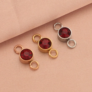 Macro view of three stainless steel birthstone charms in rose gold, gold, and silver